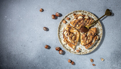 Homemade thin crepes with chocolate spread, banana and hazelnuts. breakfast or dessert. Long banner format. top view