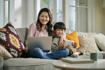 home portrait of young and happy asian mother and five-year-old son looking at camera smiling - obrazy, fototapety, plakaty