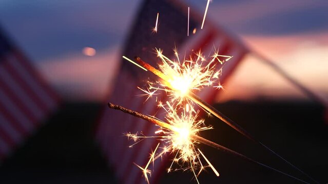 Fireworks sparklers fourth of July, Happy USA Independence Day Holiday, Celebration. Hands Holding Sparklers Fireworks with USA American Flag at sunset outdoor background. Concept 4th of July, Freedom