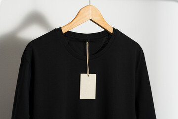 Black t-shirt with blank price tag on wooden hanger