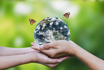 Environment day and earth day concept. Two human hands holding earth globe with butterfly flying...