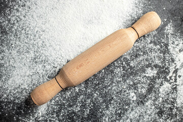 Rolling pin and flour on a dark background. banner, menu, recipe place for text, top view