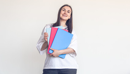 Young woman with colorful notepads on a white background, copy space.