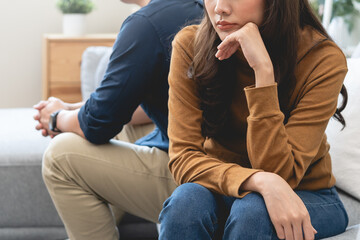 Family problem concept, Close-up hands of Asian wife sitting on sofa and husband sitting back to back in the living room at home have problems in a relationship and have an argument