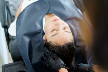 Close up shoot of Asian beautiful woman get hair washing and caring at professional salon shop,...