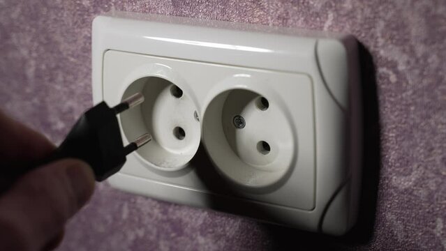 Insert the plug from the electrical appliance into the socket. Slow motion. Dolly shot