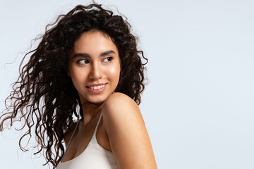 Beautiful young woman with natural makeup , and shiny curly hair on a blue background