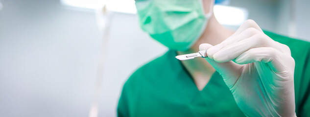 Professional surgeon holding a scalpel operating in a hospital operating room. doctor concept. copy...