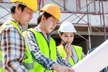 Architects, engineers and contractors holding construction drawings outdoor meeting in construction site. Industrial concept