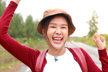 Portrait of a beautiful Asian woman wearing a hat and carrying a backpack She smiles cheerfully and enjoys nature tourism. Travel concept. Tourists hiking, camping