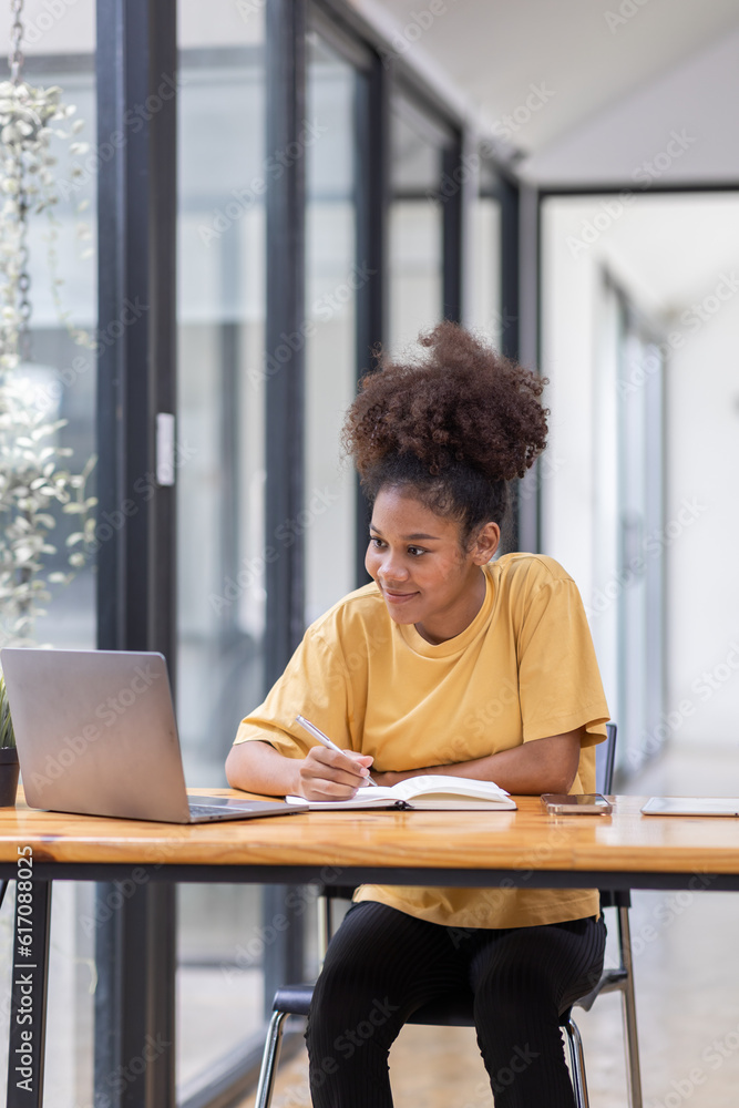 Wall mural Business And Education Concept. Smiling african american  sitting at desk working on laptop writing letter in paper documents, free copy space. Happy millennial female studying using laptop	