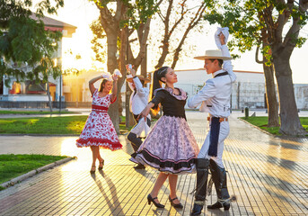 Fototapeta group of two Latin American couples of huaso dancing cueca in the town square at sunset in La Serena obraz
