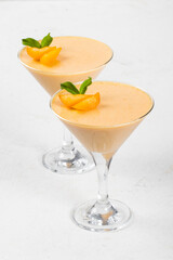Apricot cream jelly dessert, Panna Cotta, decorated with fresh apricot slices, in a martini glass. White background