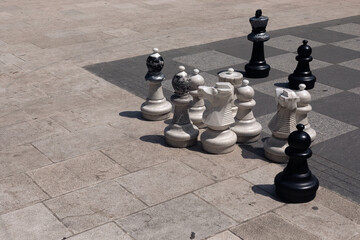 Big plastic chess figures on the stone playground in the park.