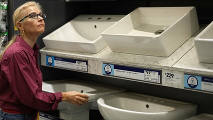 Attractive mature woman shopping looking at bathroom sinks for home renovation improvement project.