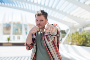 handsome man looking confident, angry, strong and aggressive, with fists ready to fight in boxing position