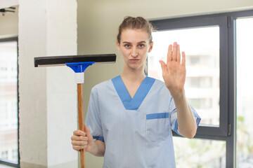looking serious showing open palm making stop gesture. windows washer concept