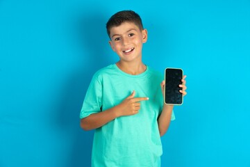 Attractive cheerful Little hispanic boy wearing green T-shirt holding in hands cell showing black screen