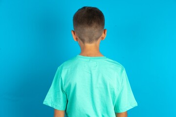 The back view of a Little hispanic boy wearing green T-shirt . Studio Shoot.