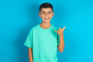 Little hispanic boy wearing green T-shirt showing up number six Liu with fingers gesture in sign...