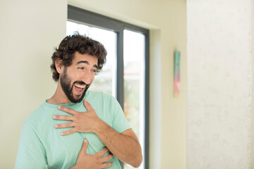 young crazy bearded man laughing out loud at some hilarious joke, feeling happy and cheerful, having fun