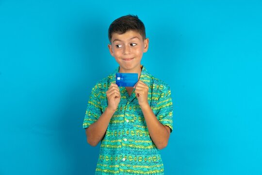 Photo of cheerful Little hispanic boy wearing green aztec shirt hold debit card look empty space