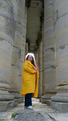 Fototapeta na wymiar Girl in yellow cloak near ancient Greek columns