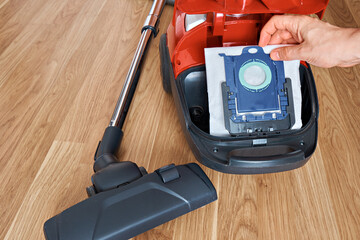 Man's hand inserting a new garbage bag into the vacuum cleaner. View from above.