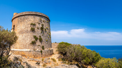 Ancient watchtower Torre Picada perched on the Port de Sóller cliffs, with its weathered stone...