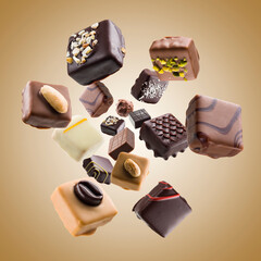 Assorted chocolate pralines falling on colored background