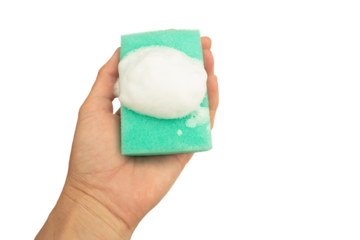 A woman's hand holds a green sponge with soapy foam isolated on a transparent background.