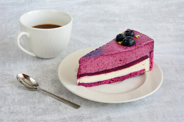 blueberry cake on the saucer with cup of coffee and teaspoon, copy space