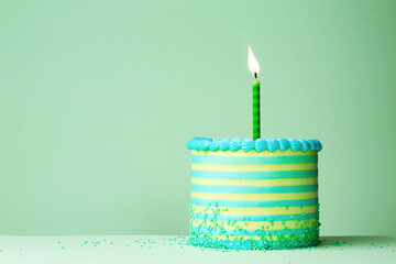 Green striped birthday cake with one birthday candle