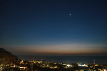 Illuminated coastal town by seascape under starry sky during nighttime at Costa Rica