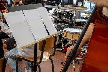 Real life young music students during rehearsals. Musical instruments and music stand with stave.