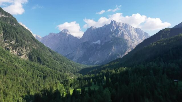 Aerial shot top view of Rocky Mountains. Sunny wether High hills on background . Green forest and valley.