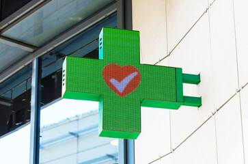 LED sign bracket in shape of green cross with a red heart in the center. Pharmaceutical sign symbol