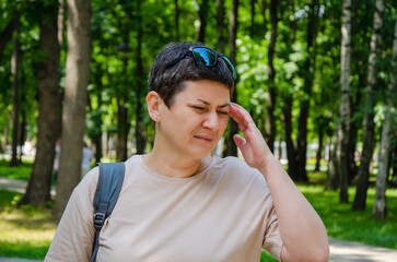 woman clutched head due to headache while walking. migraine, high blood pressure, health problems.