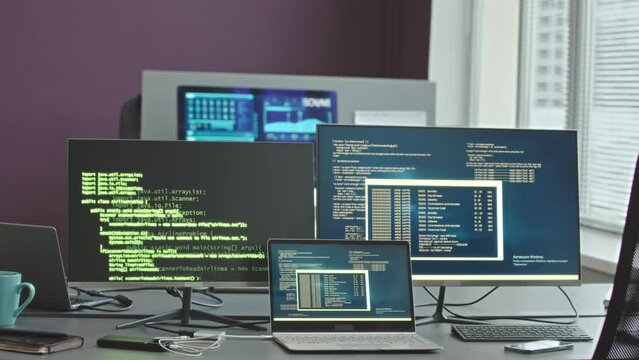 No people shot of program codes on two desktop computers and laptop on desk in cyber security agency