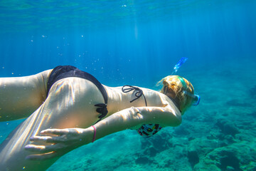 Female apnea bikini swims in crystal sea. Underwater background of a woman snorkeling and doing...