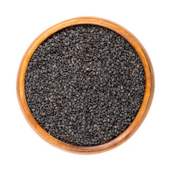Black sesame, in a wooden bowl. Unhulled seeds of Sesamum indicum, with rich and nutty flavor, and with one of the highest oil content of any seed. Used in Asian cuisine. Close-up, macro food photo.