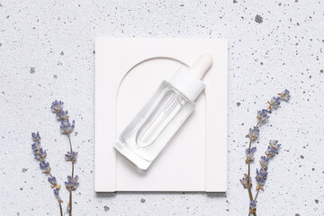 Skin care serum in glass bottle with dropper on white stone background with fresh aromatic lavender flowers top view. Natural herbal cosmetic products. 