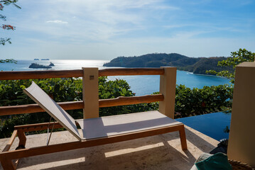 Fototapeta na wymiar Luxury resort with deckchair by swimming pool in front of beautiful seascape during sunny day at Costa Rica