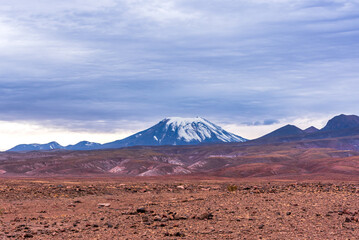 View of desert and snowy peak of volcano in Atacama