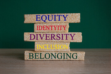 Equity, idenyity, diversity, inclusion, belonging symbol. Brick blocks with words identity, equity, diversity, inclusion, belonging on beautiful green background. Inclusion, belonging concept.