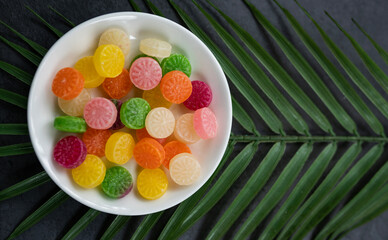 Round jelly candies in white bowl with green leaf on the background, Kerala sweet mittai concept image