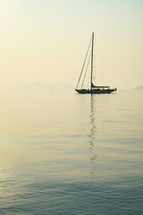 Silhouette of a sailing yacht in early morning sunlight, island of Spetses, Aegean Sea, Greece