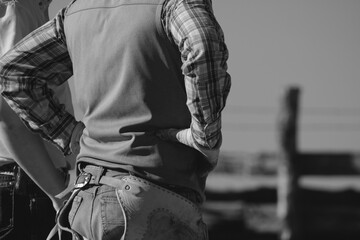 Fototapeta premium Western lifestyle shows cowboy on ranch in black and white, hands on hips.