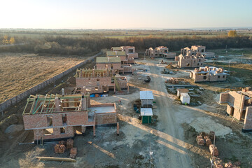 Aerial view of new homes with brick framework walls under construction in rural suburban area. Development of real estate in modern city suburbs