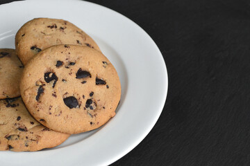 Cookies for tea with chocolate drops on a black table